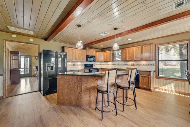 a kitchen with stainless steel appliances kitchen island granite countertop wooden floors and wooden cabinets