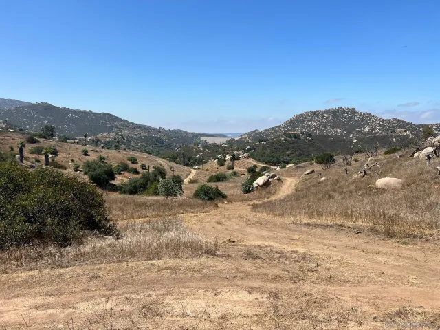 a view of a dry field with mountains in the background