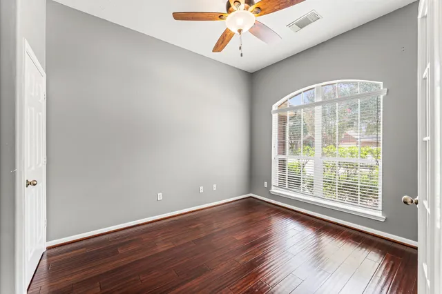 a view of an empty room with wooden floor and a window