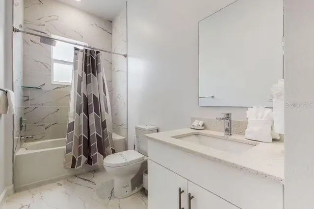 a bathroom with a granite countertop sink a toilet and shower