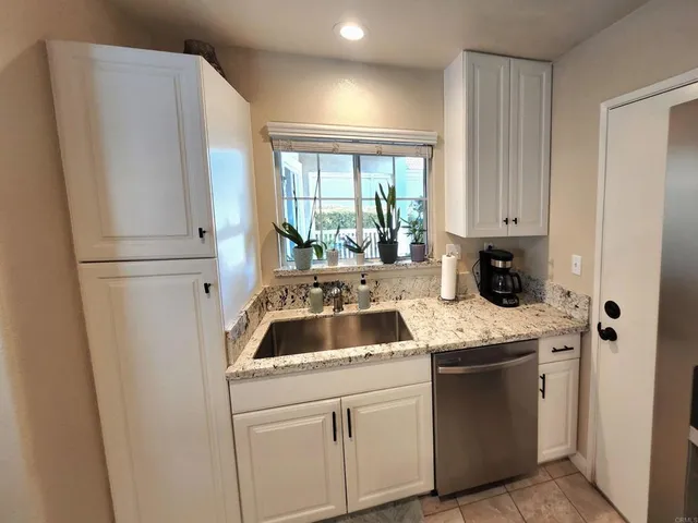 a kitchen with granite countertop a sink stove and refrigerator