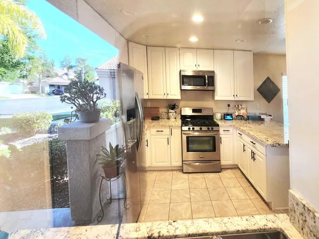 a kitchen with stainless steel appliances kitchen island granite countertop a stove a sink and a refrigerator