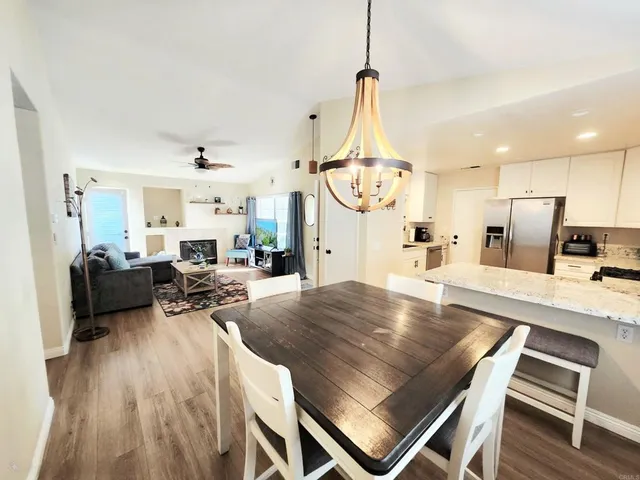 a very nice looking open kitchen with stainless steel appliances kitchen island granite countertop a refrigerator stove oven with white cabinets and wooden floor