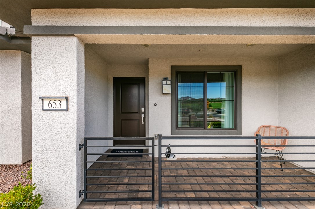 653 Pickled Pepper Place Henderson, NV 89011 - Photo 3 of 35 A welcoming entry invites with a modern railing, textured walls, and a large window reflecting scenic outdoor views.
