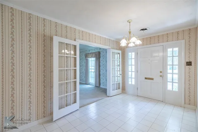 a view of a hallway with chandelier and glass door