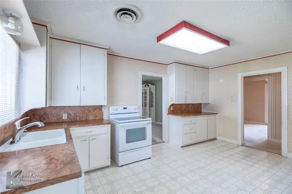 a kitchen with white cabinets and sink
