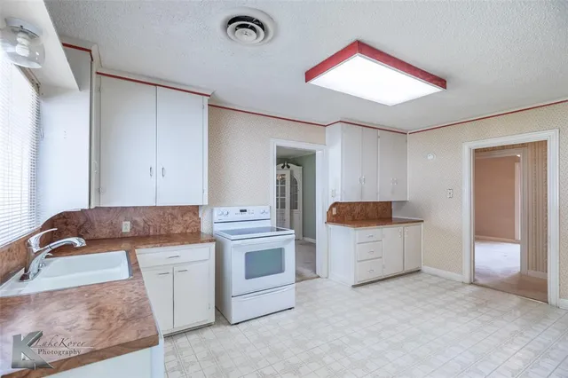 a kitchen with white cabinets and sink