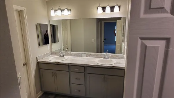 a bathroom with a toilet sink double vanity granite and mirror
