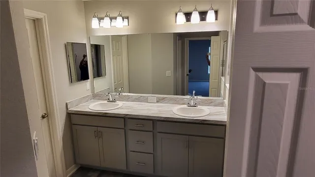 a bathroom with a toilet sink double vanity granite and mirror
