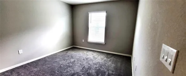 a view of an empty room with closet and a window