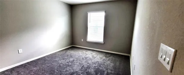 a view of an empty room with closet and a window