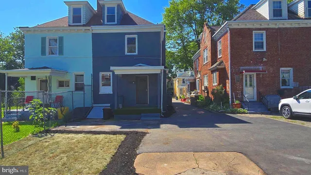 a view of a brick house with many windows plants and large tree