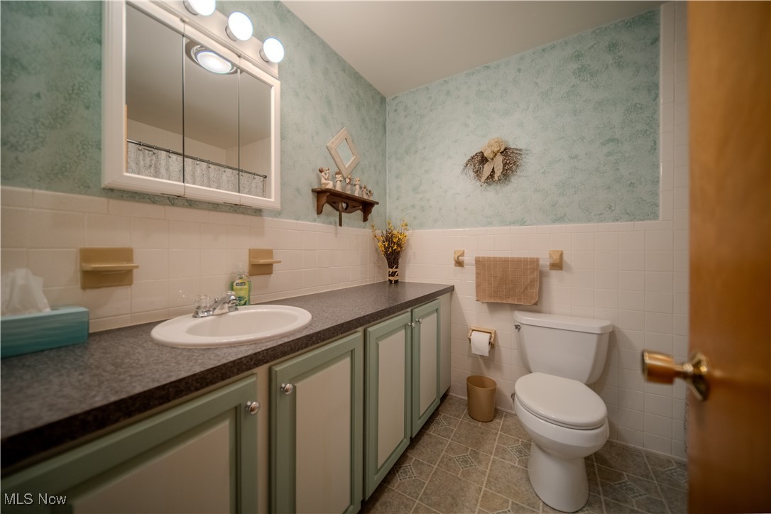 3447 Marian Road Ravenna, OH 44266 - Photo 16 of 35 Bathroom with wallpapered walls, vanity, tile walls, light tile patterned floors, and curtained shower