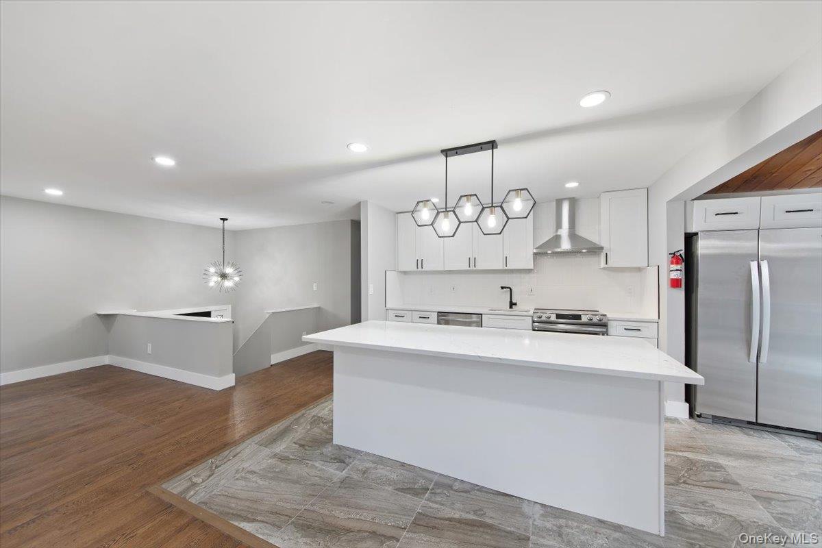 96 Fairmont Road Mahopac, NY 10541 - Photo 8 of 34 Open-concept kitchen featuring a large island with white countertop, stainless steel appliances, a geometric pendant light fixture, and light-toned cabinetry