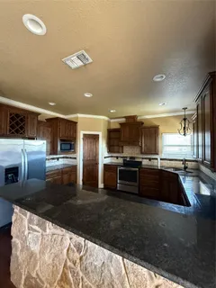 a large kitchen with a large counter top stainless steel appliances and cabinets