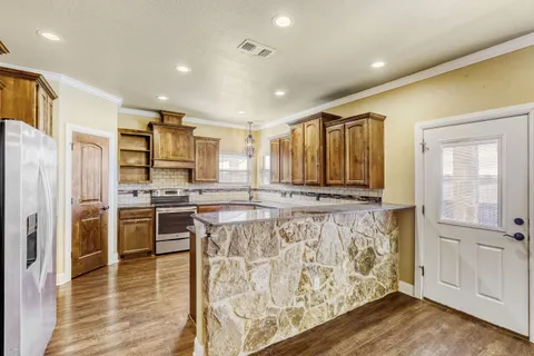 a kitchen with stainless steel appliances granite countertop a refrigerator and a stove top oven