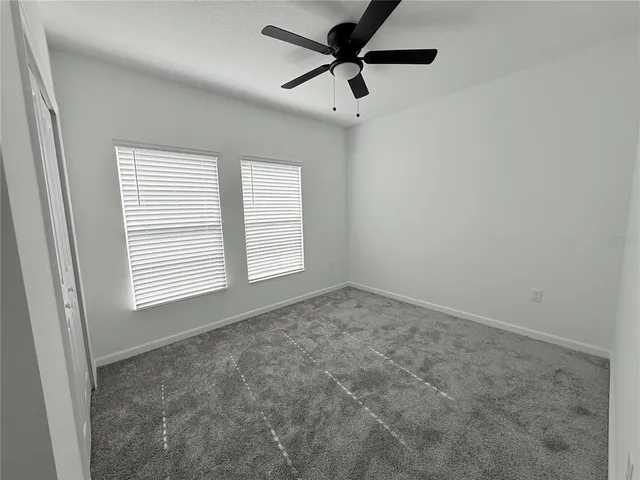 an empty room with a window and a fan