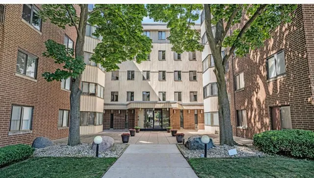a front view of a residential apartment building with a yard and potted plants