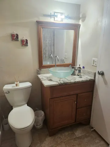 a bathroom with a granite countertop toilet sink and mirror