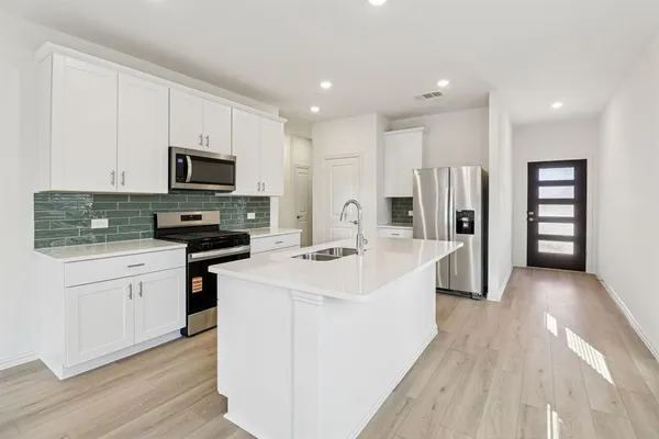a kitchen with kitchen island white cabinets sink and stainless steel appliances