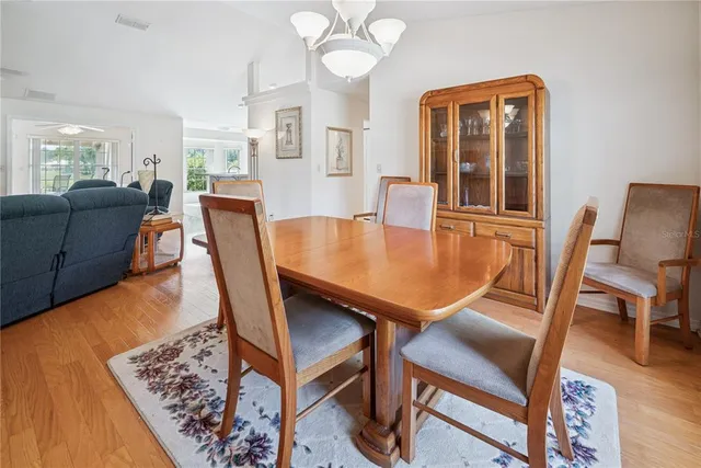 a dining room with wooden floor a chandelier a wooden table and chairs