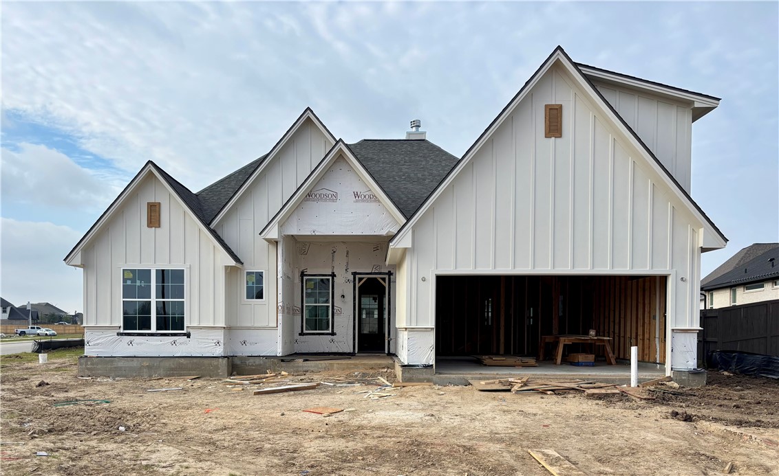 Front elevation showing tall gables, creamy white board and batten siding, and large windows. 
