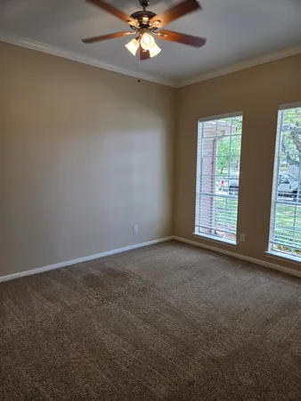 an empty room with windows and chandelier fan