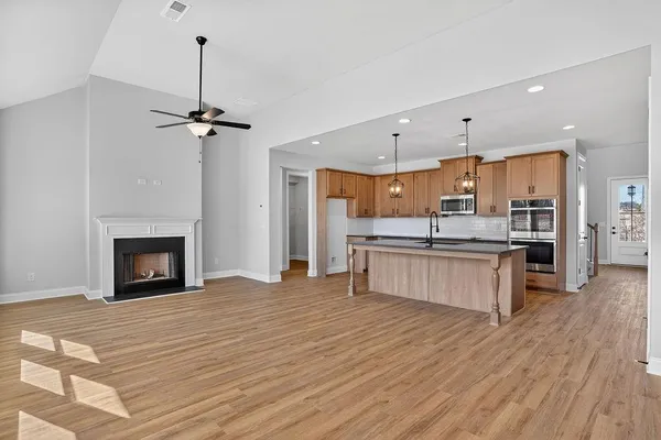 a kitchen with stainless steel appliances granite countertop a sink a microwave oven a refrigerator and wooden floors