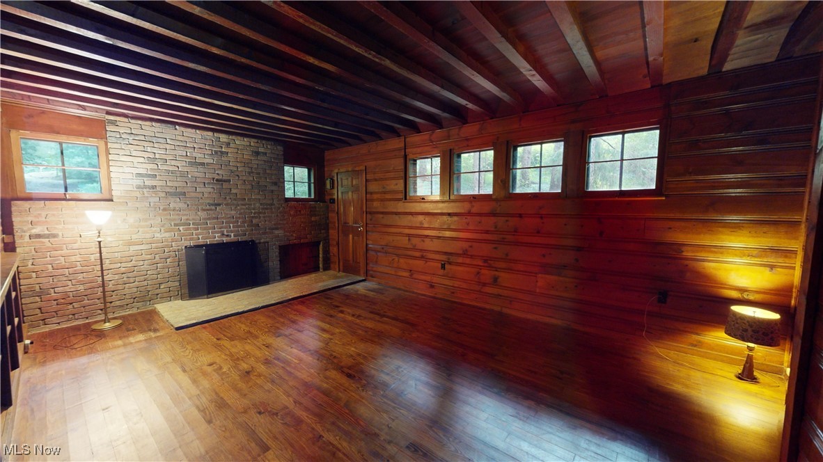 13696 Sperry Road Novelty, OH 44072 - Photo 2 of 40 Unfurnished living room with brick wall, beamed ceiling, a brick fireplace, and wood-type flooring