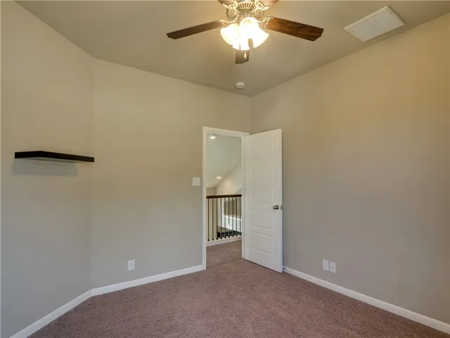 an empty room with a chandelier fan and a window