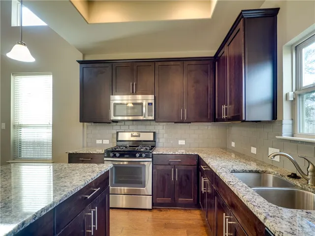 a kitchen with kitchen island granite countertop a sink cabinets and stainless steel appliances