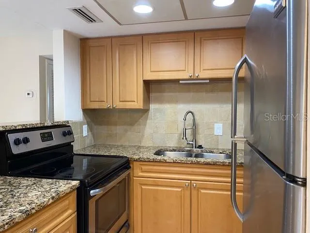a kitchen with stainless steel appliances granite countertop a sink stove and cabinets