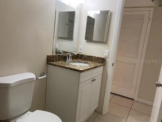 a bathroom with a granite countertop toilet sink and mirror
