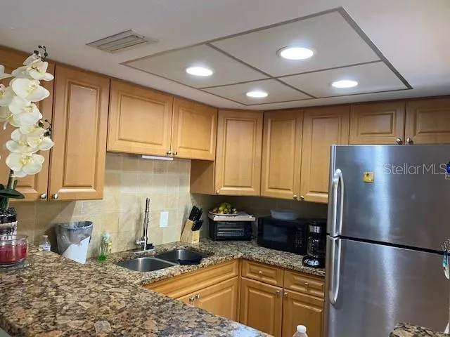 a kitchen with stainless steel appliances granite countertop a refrigerator a sink dishwasher a stove and a microwave oven on granite countertops