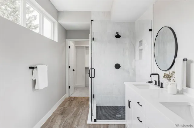 a bathroom with a granite countertop sink a mirror and shower