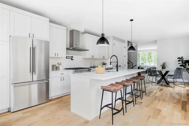 a kitchen with stainless steel appliances granite countertop a sink a stove a refrigerator and island with wooden floor