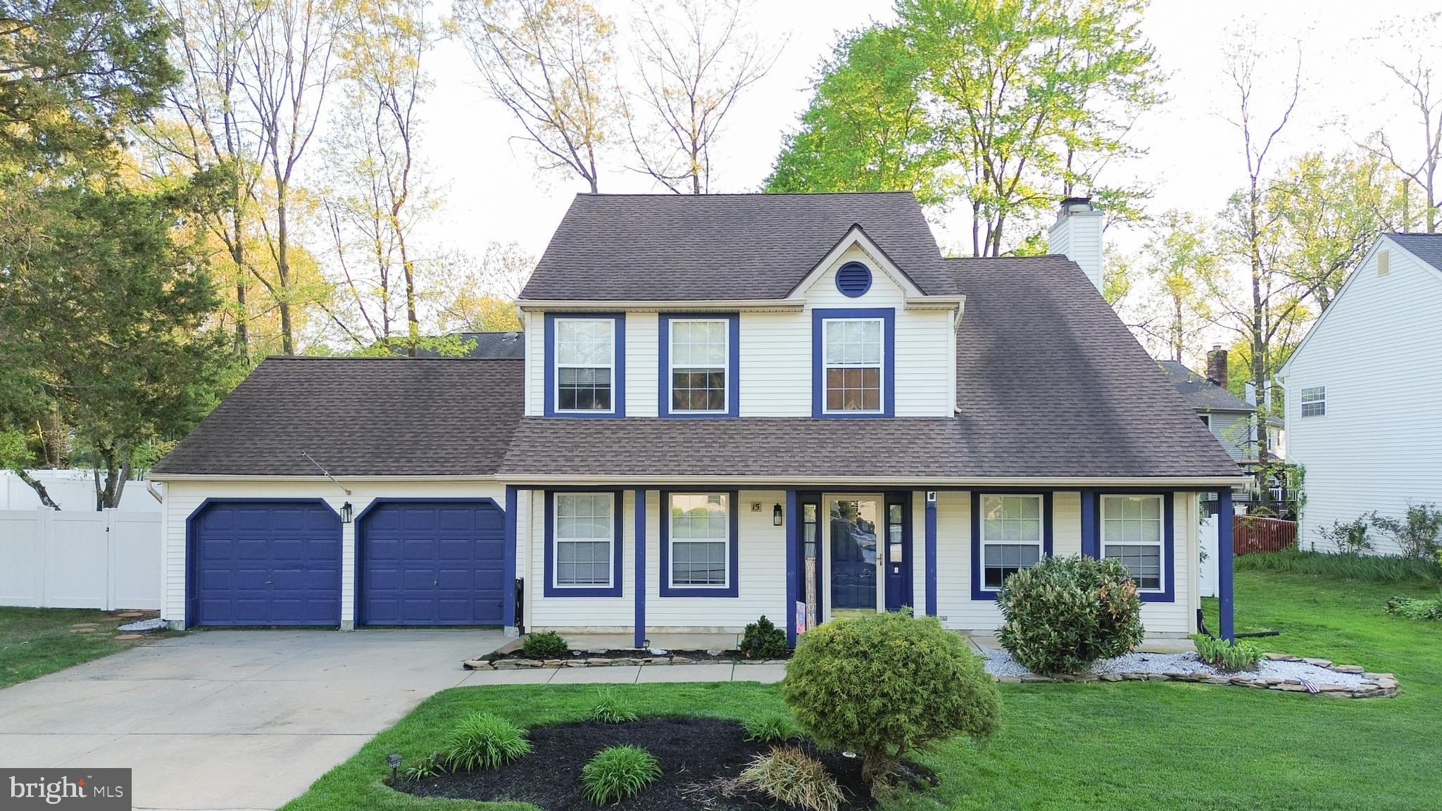 a front view of a house with garden and trees
