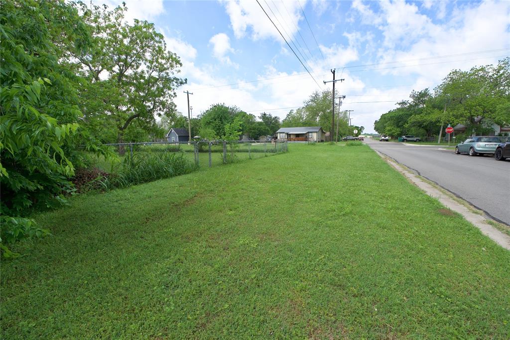 714 Potter Street Gainesville, TX 76240 - Photo 11 of 12 The property features an expansive grassy area with mature trees and a chain-link fence