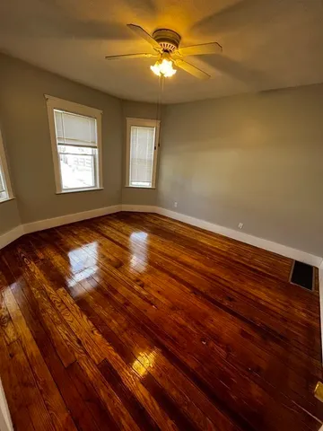 a view of empty room with wooden floor and fan
