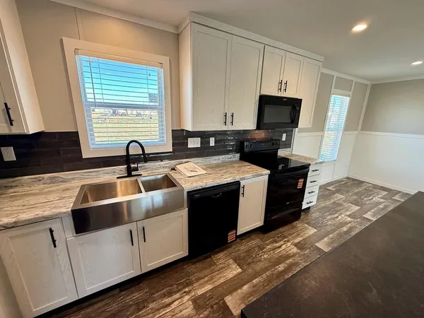 a kitchen with kitchen island granite countertop a sink a counter top space and cabinets