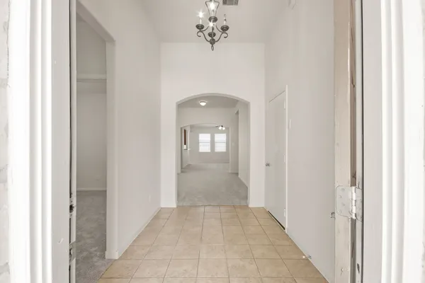 a view of a hallway with wooden floor and a chandelier