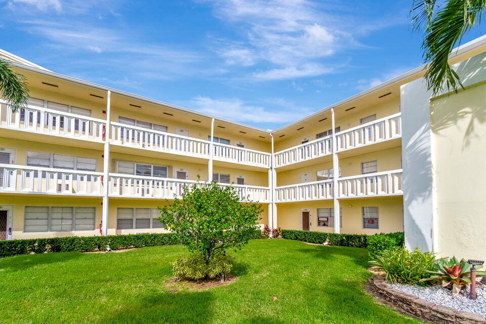150 Dorset D, Unit 150 Boca Raton, FL 33434 - Photo 3 of 82 a view of a large building with a big yard and plants