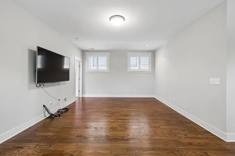 an empty room with windows tv and wooden floor