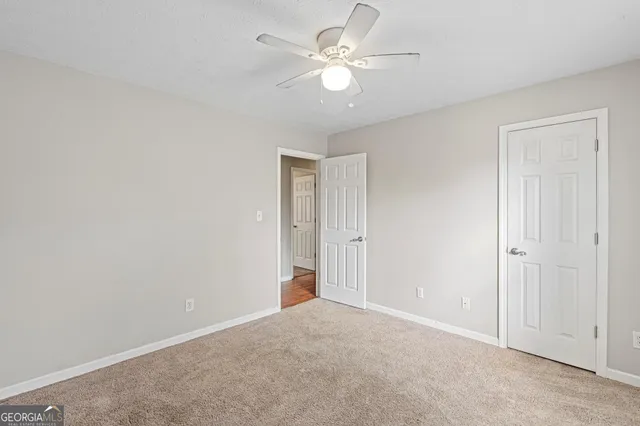 a view of an empty room with chandelier fan and fire place