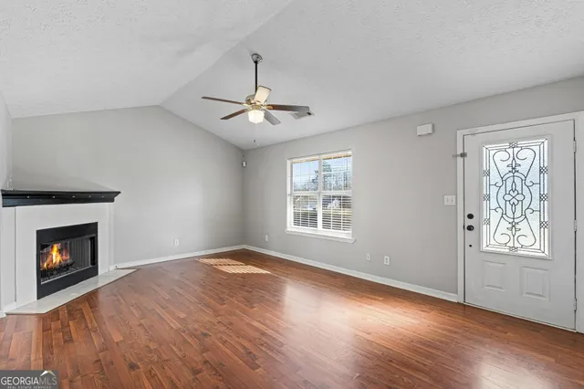 a view of an empty room with wooden floor fireplace and a window