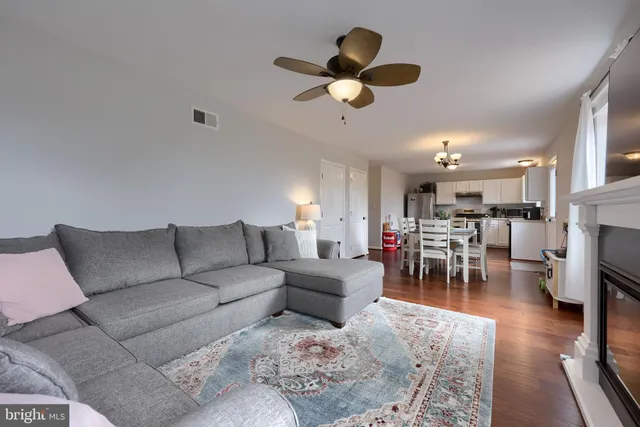 a living room with furniture kitchen view and a chandelier