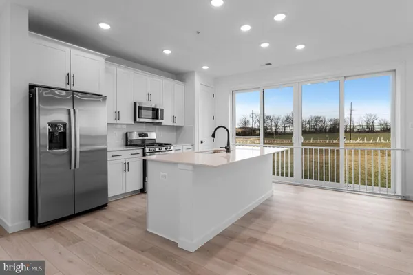 a large kitchen with stainless steel appliances granite countertop a refrigerator a sink dishwasher a stove and a microwave oven on the wooden floor