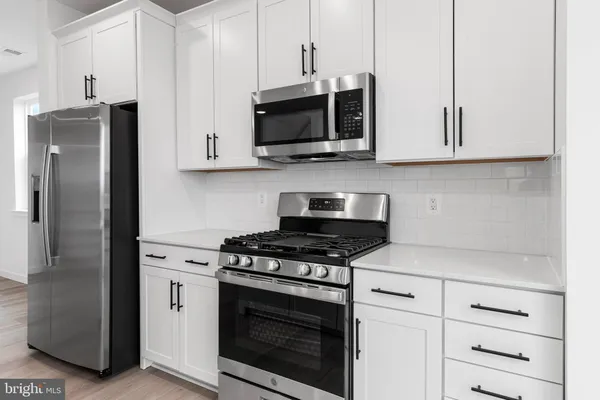 a kitchen with stainless steel appliances white cabinets and a stove a refrigerator with a sink
