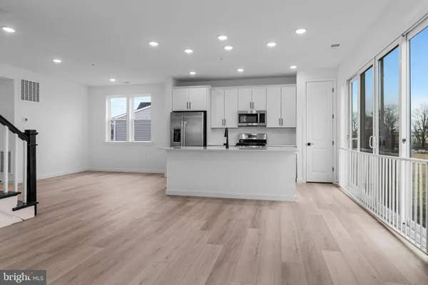 a large kitchen with stainless steel appliances a large counter top a wooden floor and a window
