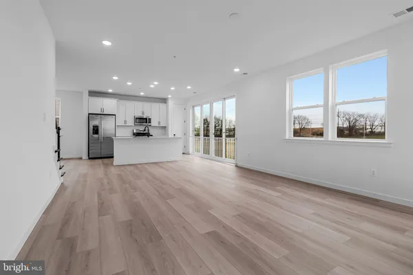 a view of a kitchen with a fridge and wooden floor